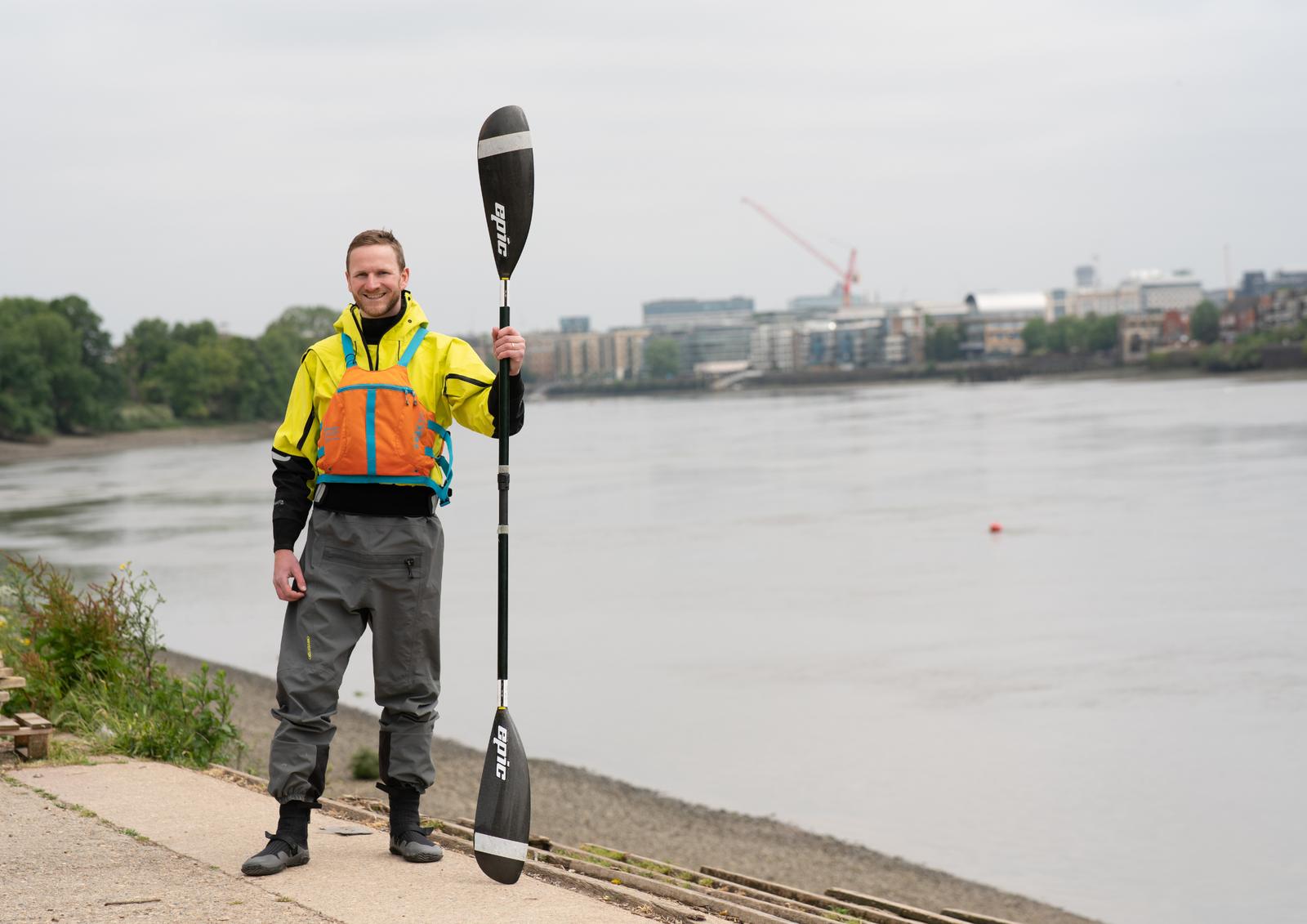 Mark Agnew holding a kayak paddle beside the River Thames in London
